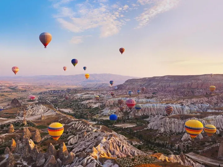 Kapadokya sıcak hava balonu turu — şafak vakti peri bacaları üzerinde balonlar